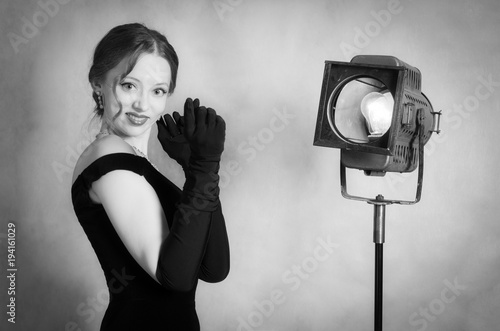 Beautiful girl in evening dress and long gloves posing in studio. Black and white portrait in retro style