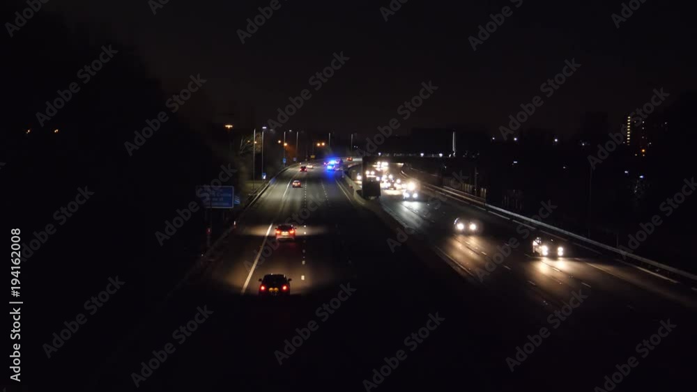 M60 motorway at night scene, view from above of ambulance van rushing away with blue lights flashing M60 motorway at night scene, view from above of ambulance van rushing away with blue lights flashing