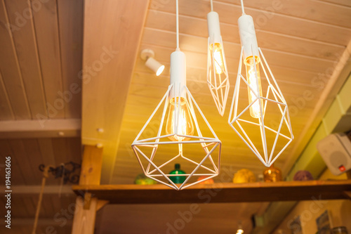 3 modern chandeliers hanging under ceiling and give a warm yellow light, close up
