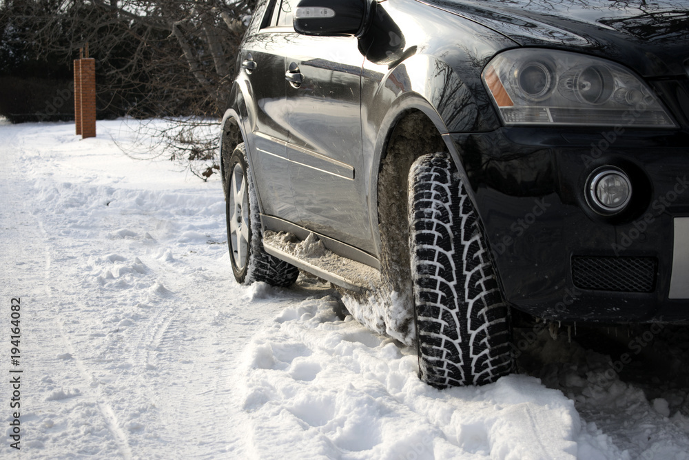 Naklejka premium Close-up portrait of a black car on a snowy road. Black car. Winter. wheels. headlights. white snow. winter nature. power. speed