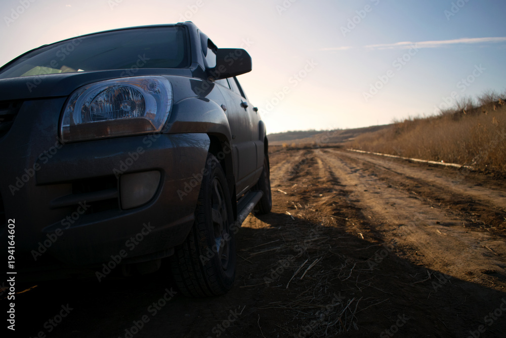 SUV in the field at sunset, car and a road, headlight, warm, dusty evening SUV in the field at sunset, car and a road, headlight, warm, dusty evening