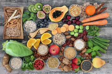 High dietary fibre health food concept with fruit, vegetables, whole wheat pasta, legumes, cereals, nuts and seeds  with foods high in omega 3, antioxidants, anthocyanins, smart carbs and vitamins.