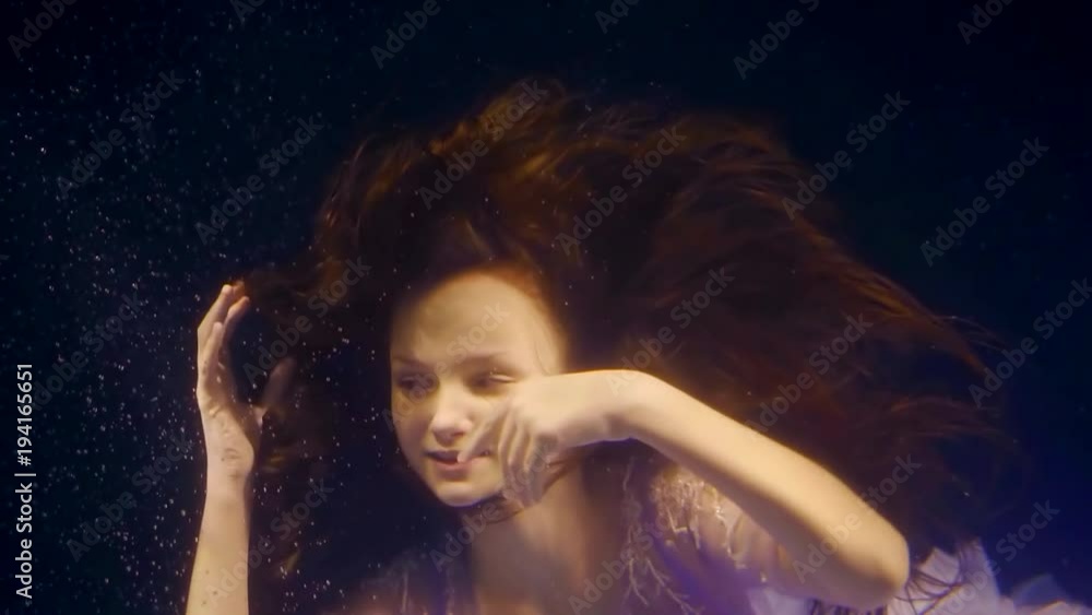 Portrait of beautiful little princess swimming underwater in purple dress. Portrait of beautiful little princess swimming underwater in purple dress.