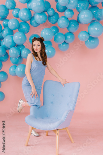 girl in a blue dress in a pink room with a blue chair and blue balls © Ilya.K