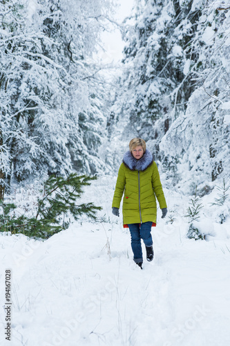 A young woman is walking through the winter forest