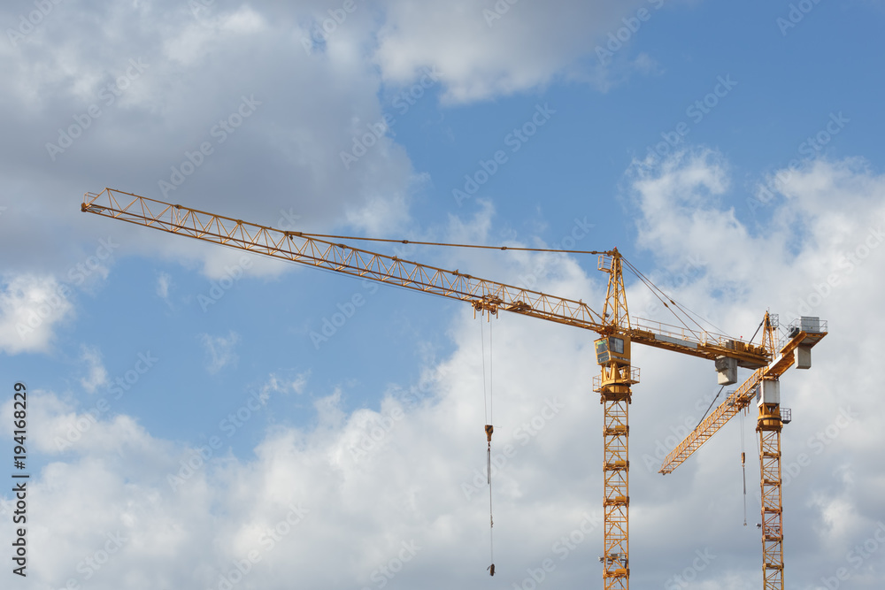 Construction cranes on the construction site on the background of clouds