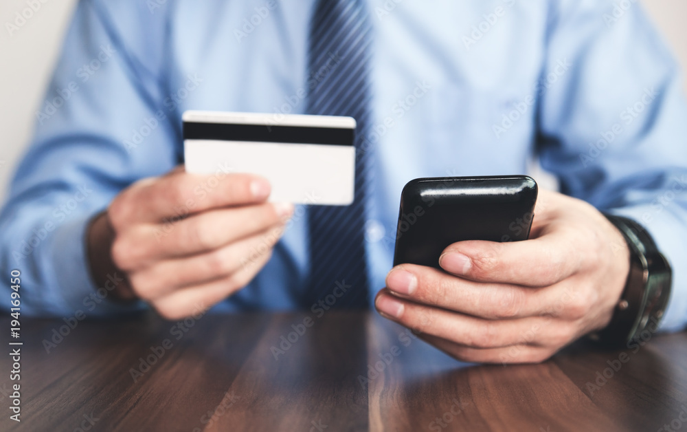 Man holding credit card and using phone. Man holding credit card and using phone.