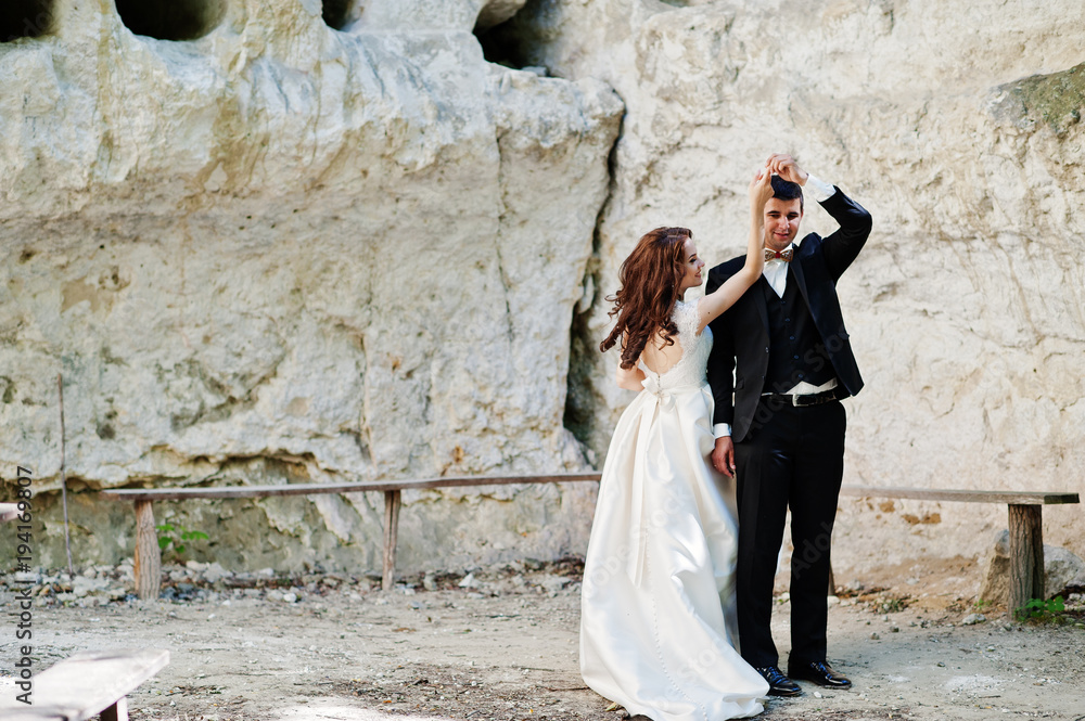 Wedding couple against cave at summer day. Wedding couple against cave at summer day.