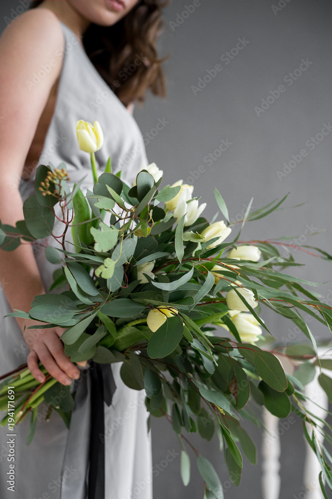 Bouquet of eucalyptus and tulips in the girl's hand