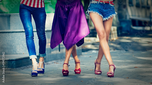 womens legs walking. Closeup photo of three modern stylish women walking on street