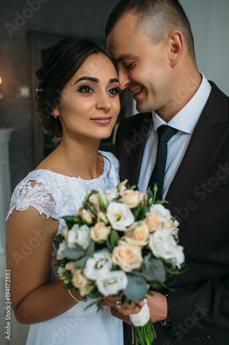Tender wedding couple poses in a cosy grey room