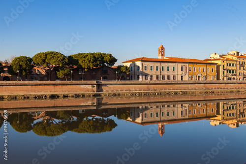 Arno river with building facades and trees reflection. Pisa, Tuscany, Italy, Europe.