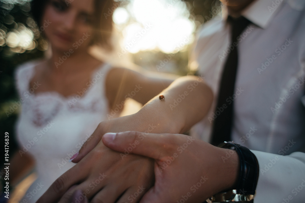 Groom holds bride's hand with a bug