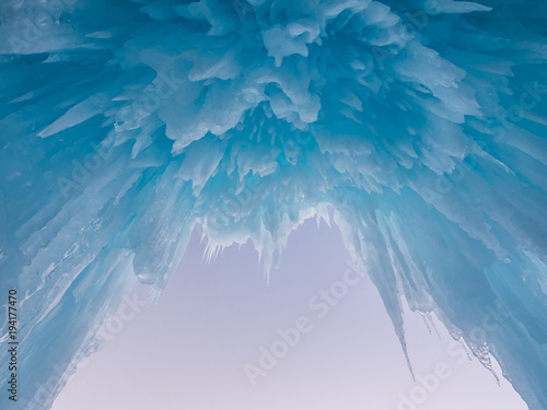 Winter ice castle caves with frozen icicles at sunset.