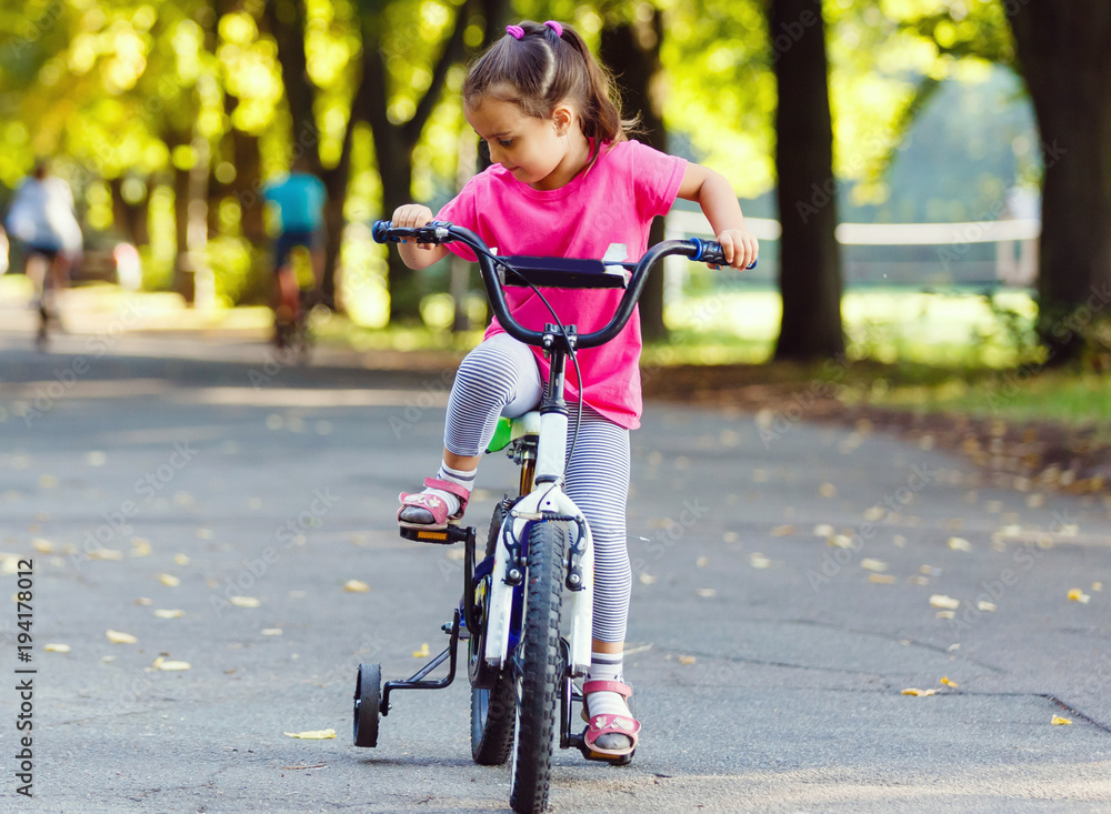 mother goes on rollers. Daughter riding a bicycle mother goes on rollers. Daughter riding a bicycle