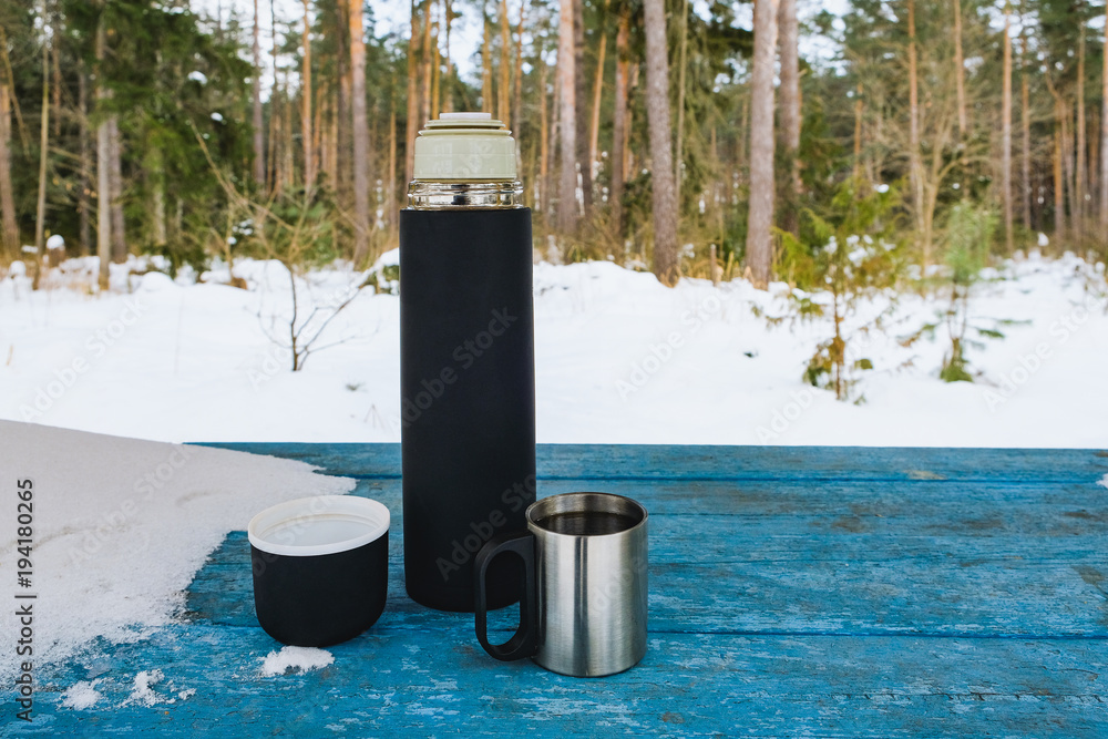 mug and thermos on the table in winter mug and thermos on the table in winter