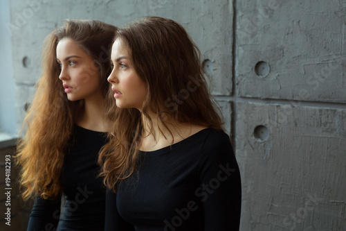 portrait of two beautiful young girls of twin sisters with flowing hair