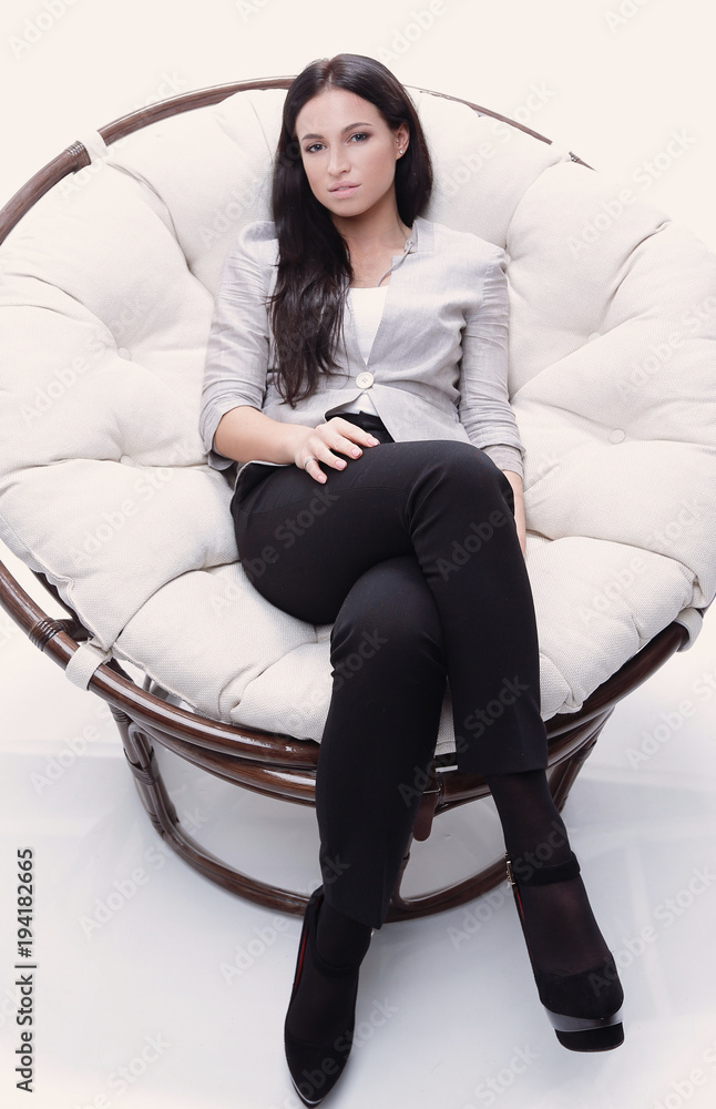 Modern young woman sitting in a round cozy soft chair Modern young woman sitting in a round cozy soft chair