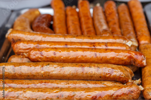 Fresh, hot sausages cooked on the grill, outdoors, on the coals.