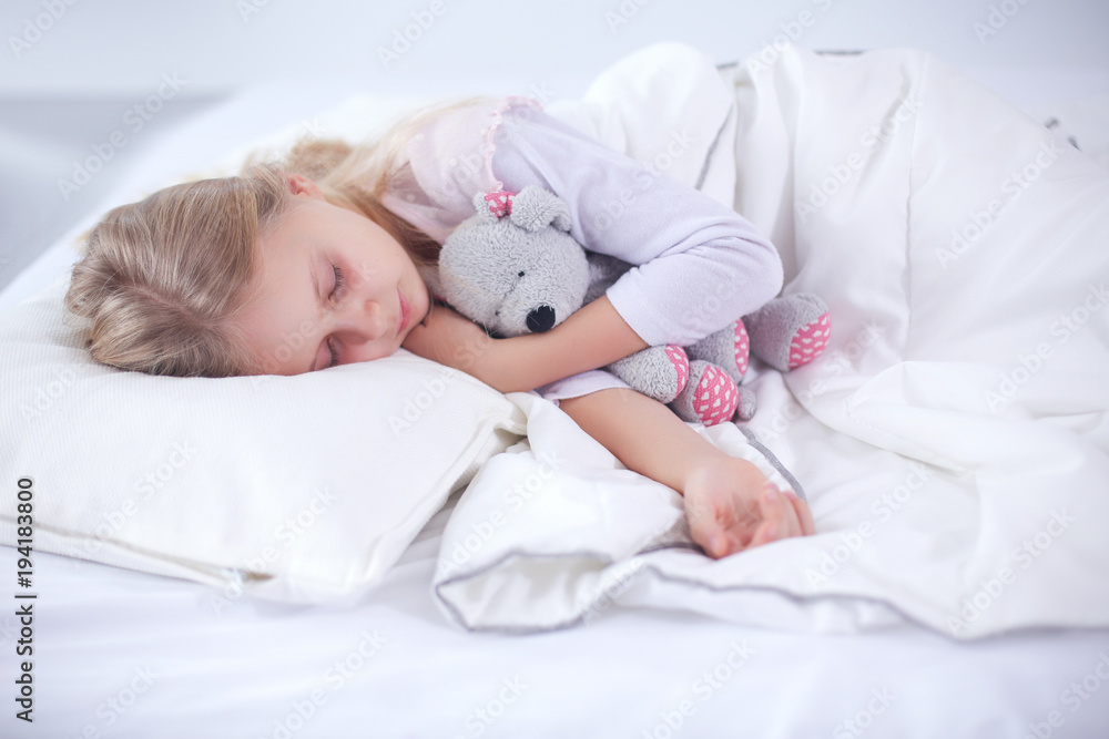 Child little girl sleeps in the bed with a toy teddy bear Child little girl sleeps in the bed with a toy teddy bear