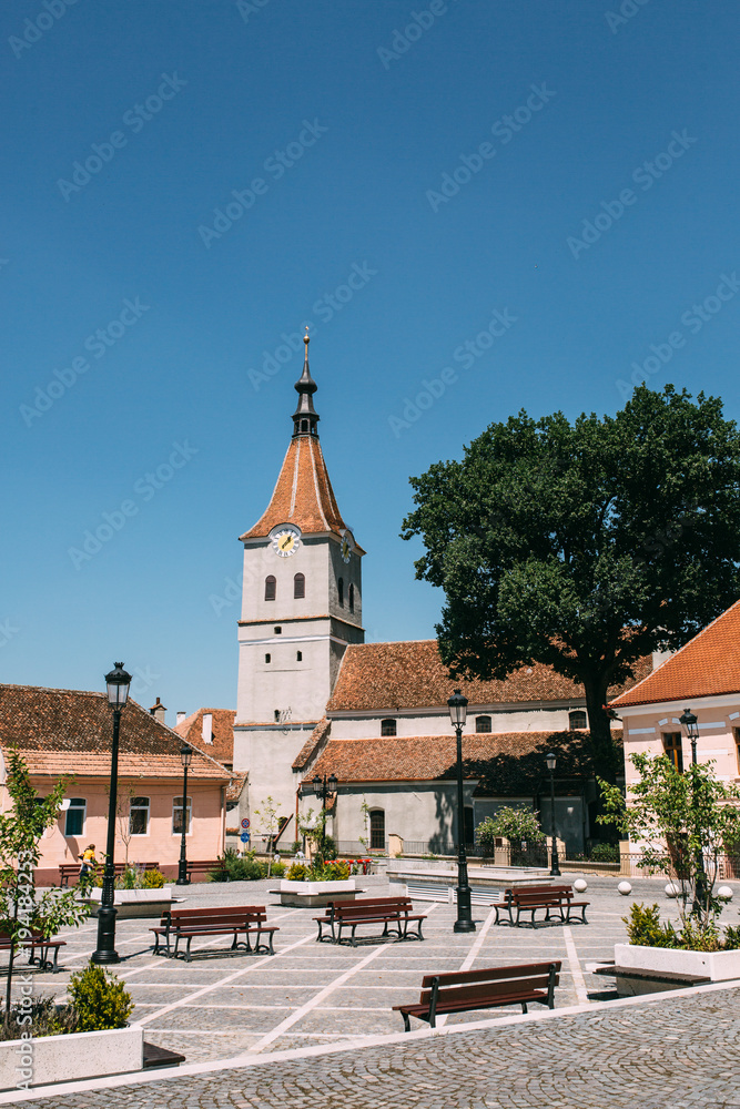 Main street of ancient Saxon town on bright sunny day. Fortified church and medieval castle on the hill. Location Rasnov, Transylvania, Romania. Picturesque vertical travel destination postcard.