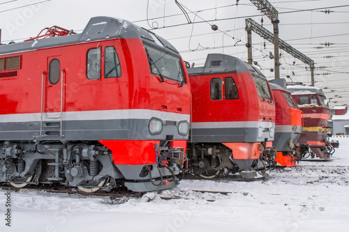 Electric locomotives are lined up on the railway in winter snow depot.
