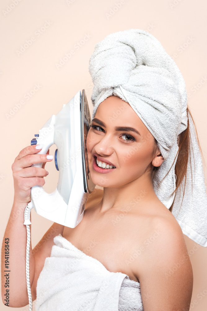 Sexy young cheerful beautiful woman after shower wearing white bathrobe and  bath towel on head holding iron on face on pastel background. Girl  housewife shocked household work Stock Photo | Adobe Stock