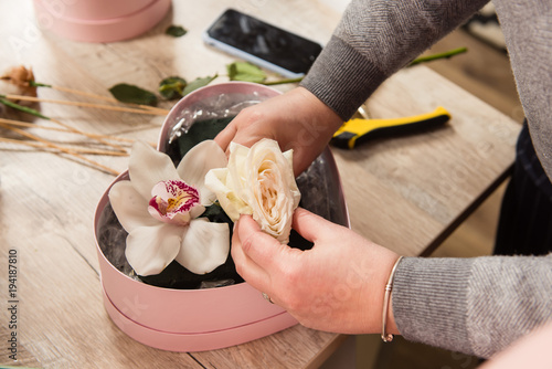 Female florist hands arrange floral composition photo