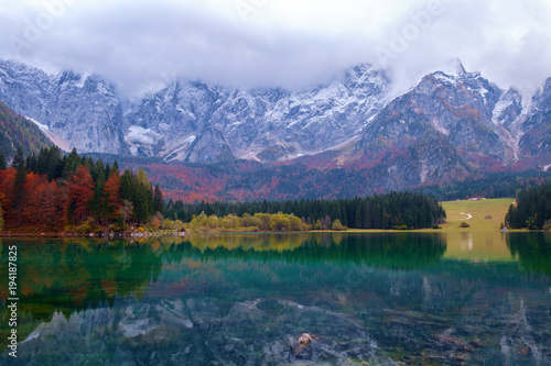Beautiful Lago di Fusine mountain lake in autumn and Mangart mountain in the background at sunset