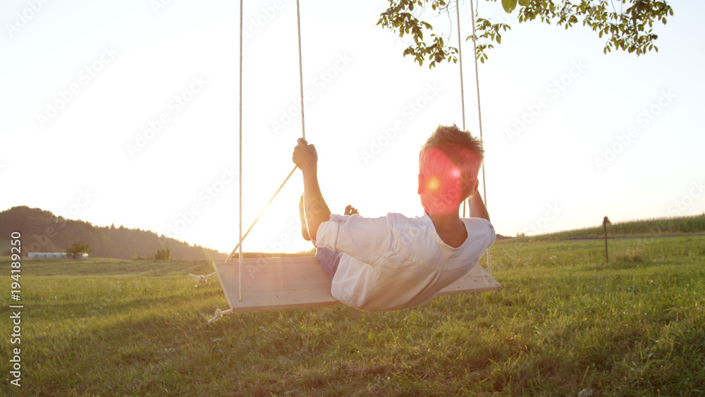 Fototapeta premium Joung boy swinging on a swing