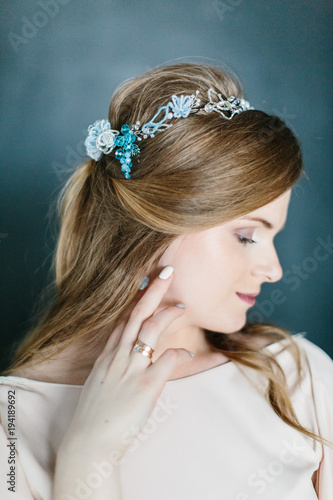 Young beautiful pregnant woman with a beautiful diadem in the hair poses standing on dark background.