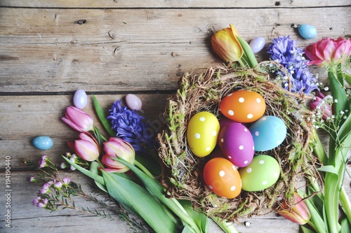 Ostern - Nest mit Eiern auf Holz und Frühlingsblumen