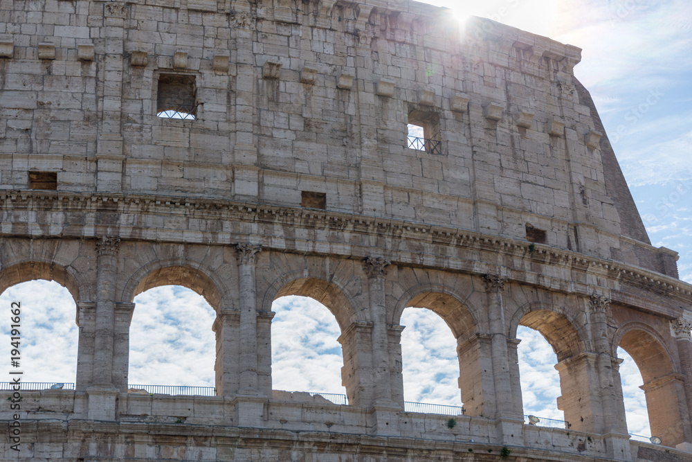detail view of beautiful architecture of historic colosseum in rome italy on sunny day and clouds