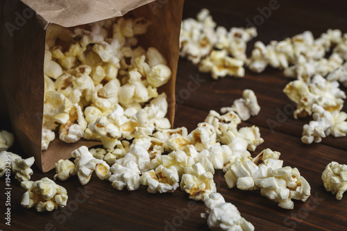 Popcorn in paper bag on wooden table