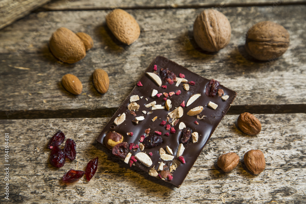 Pieces of black, chocolate with cranberry , nuts and almond on wood background Pieces of black, chocolate with cranberry , nuts and almond on wood background
