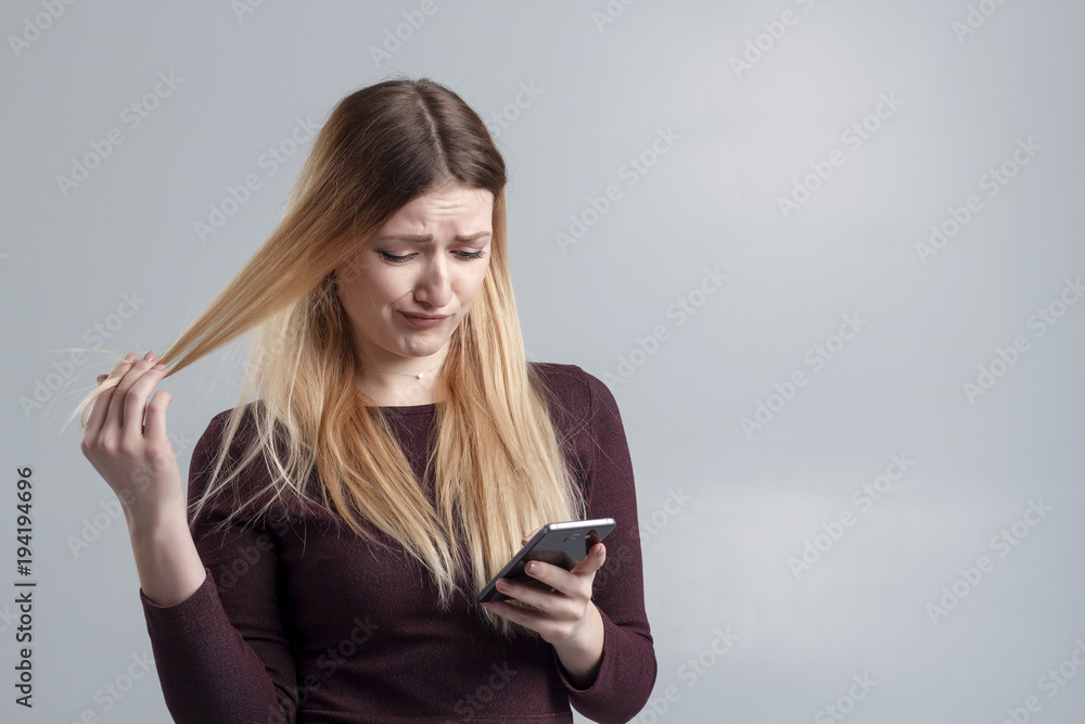 A girl in a burgundy dress on a white background reads an SMS from an annoying fan. A girl in a burgundy dress on a white background reads an SMS from an annoying fan.