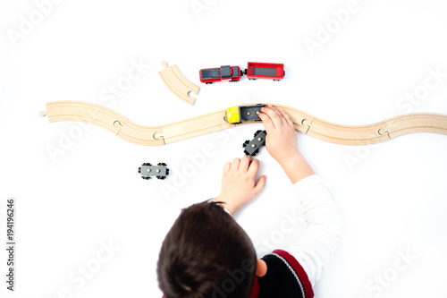Top view child playing with wooden railway, trains and cars