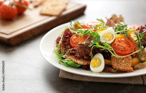 Salad with cherry tomatoes and quail eggs served on white plate, closeup