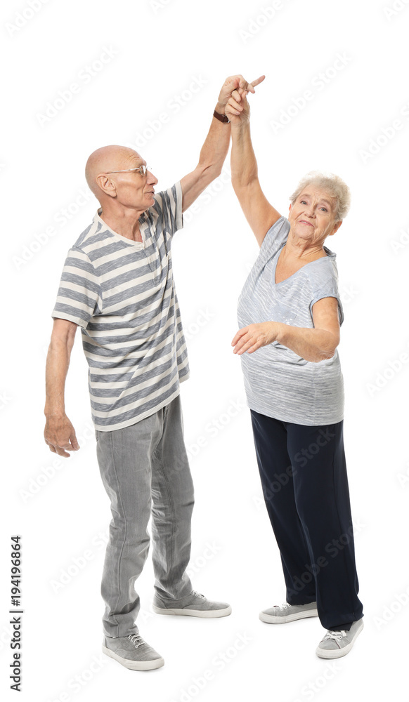 Fototapeta premium Cute elderly couple dancing against white background