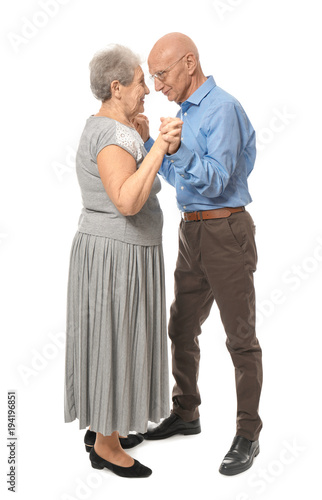 Cute elderly couple dancing against white background