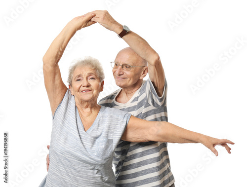 Cute elderly couple dancing against white background