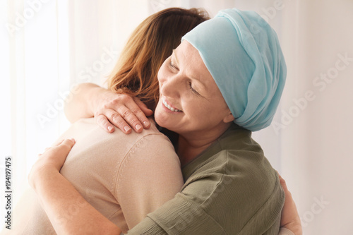 Woman hugging her mother with cancer indoors photo