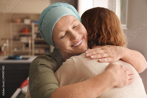 Woman hugging her mother with cancer indoors photo