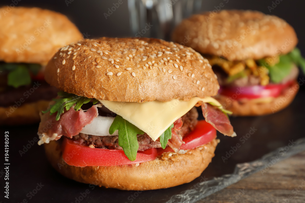 Tasty burger on slate plate, closeup Tasty burger on slate plate, closeup