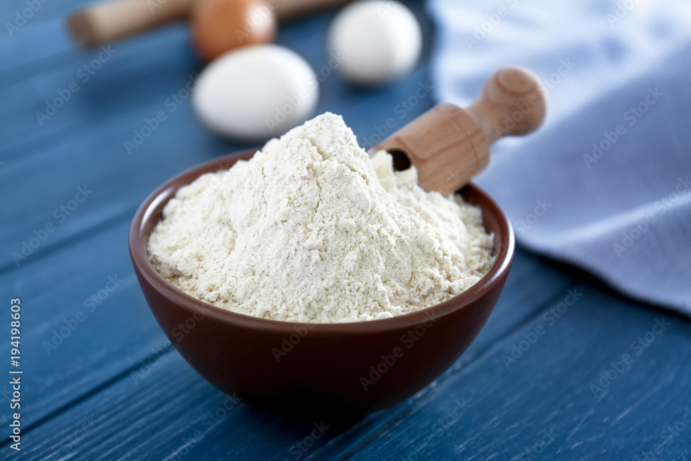 Bowl with flour on wooden table