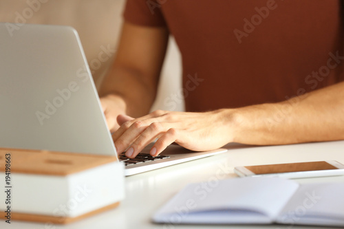 Young man working with laptop in office, closeup