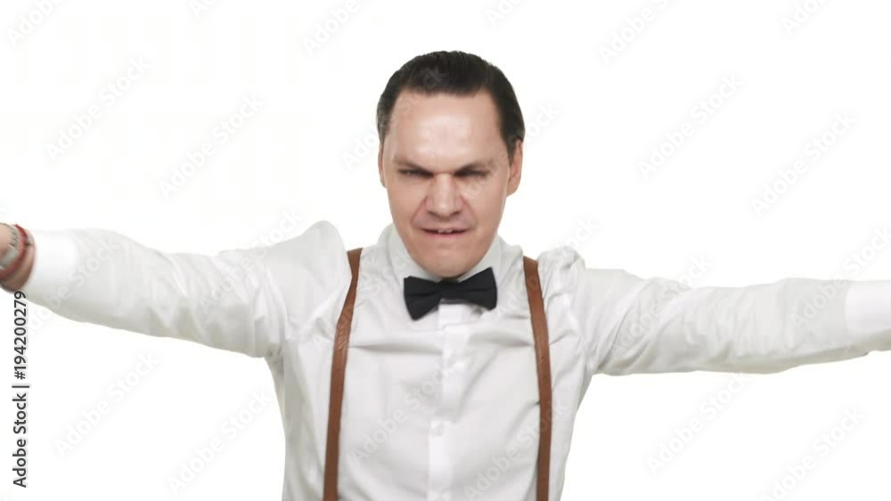 Portrait of artistic energetic man wearing white shirt and bow tie having fun while dancing and partying, over white background. Concept of emotions Portrait of artistic energetic man wearing white shirt and bow tie having fun while dancing and partying, over white background. Concept of emotions