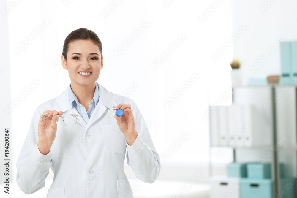 Female doctor holding contact lens case and glasses indoors Female doctor holding contact lens case and glasses indoors