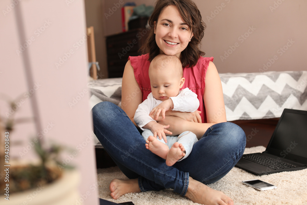 Young mother with baby sitting on carpet at home Young mother with baby sitting on carpet at home