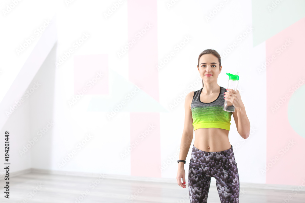 Beautiful young woman with bottle of water after doing fitness exercises at home Beautiful young woman with bottle of water after doing fitness exercises at home